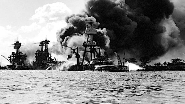 A historical photo of Battleship Row after the Japanese attack on Pearl Harbor, December 7, 1941. The battleship USS Arizona is in the center, burning furiously. To the left is USS Tennessee and the sunken USS West Virginia. (U.S. Navy photo)